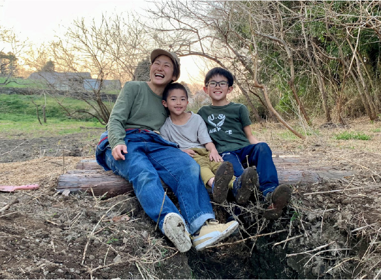 丸太に家族3人並んで座っている