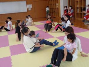 おやこ体操教室の様子　お母さんがお子さんを膝の上にのせて歩いています