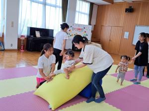 おやこ体操教室の様子　ビーズソファを滑り降りようとするお子さんを先生が笑顔で支えています