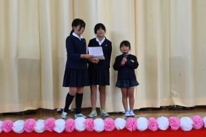 女児3人がお祝いのメッセージを読んでいる写真です。