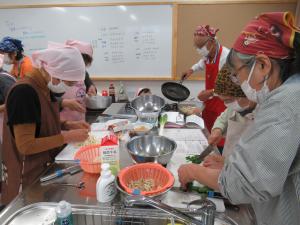 食生活改善推進員会吉田地区と参加者たちが調理をしている写真です。