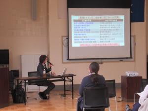 スクリーンにうつった資料について説明している講師の写真です。