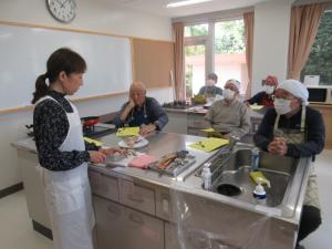 講師が料理の見本を作っているのを真剣に見ている写真です