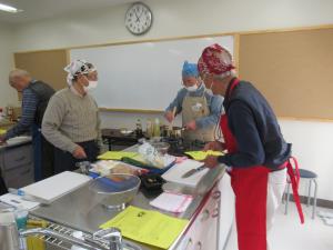 レシピを見ながらみんなで協力しあい料理をしている写真です