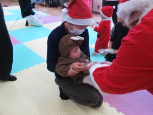 サンタさんからプレゼントをもらう子供の写真です。