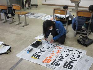 小学生が教室の床で書道をしている様子