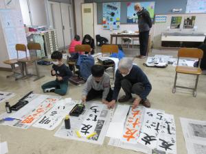 児童が先生の指導を聞きながら書道をしている様子