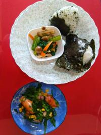 おにぎりとホウレンソウの炒め物がお皿にのっている写真