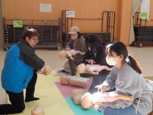 お母さんたちが子どもの人形を使って講習を受けている写真です①