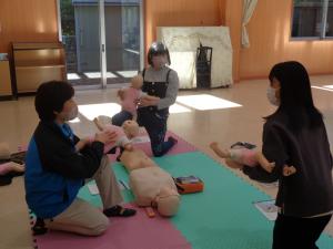 お母さんたちが子どもの人形を使って講習を受けている写真です②