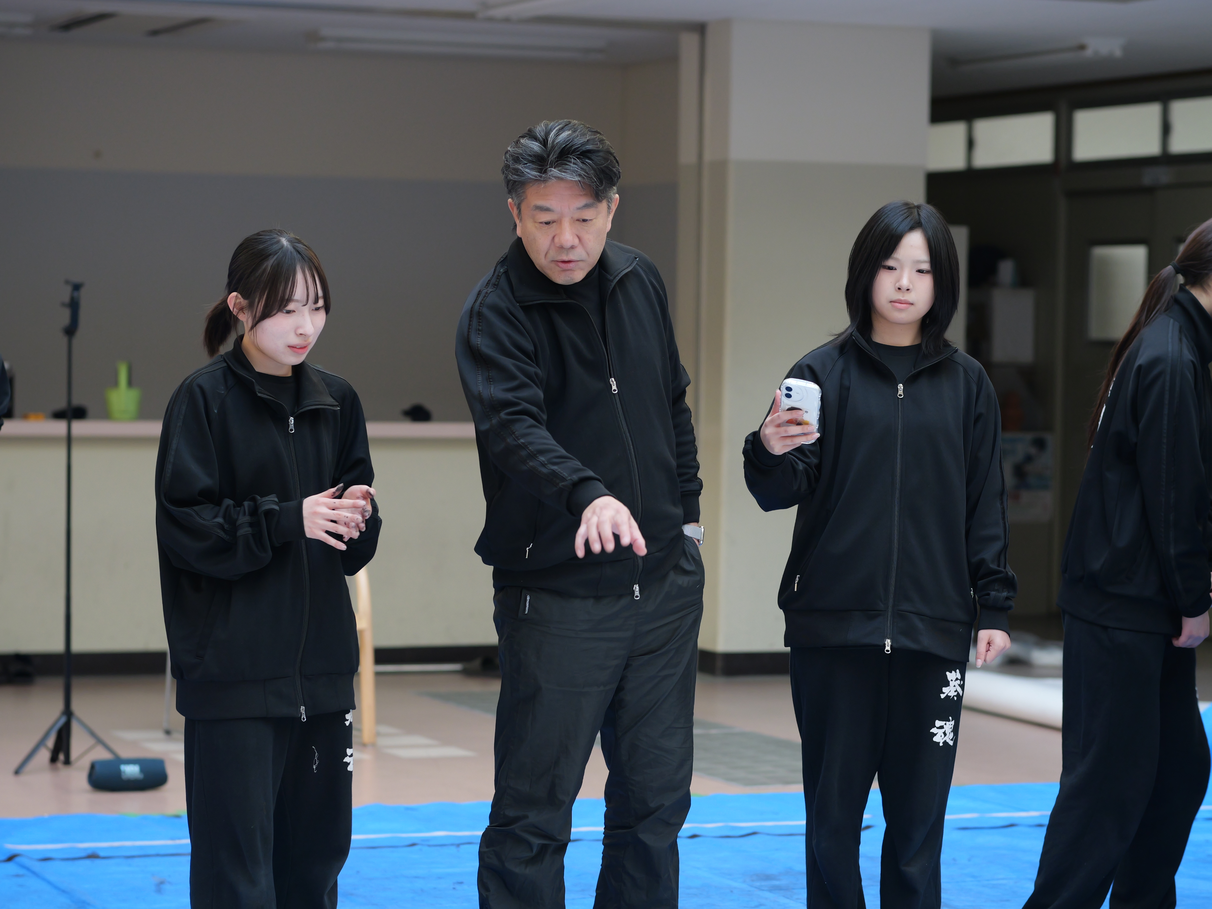 辻先生が指導している。その様子を別の生徒が録画している。
