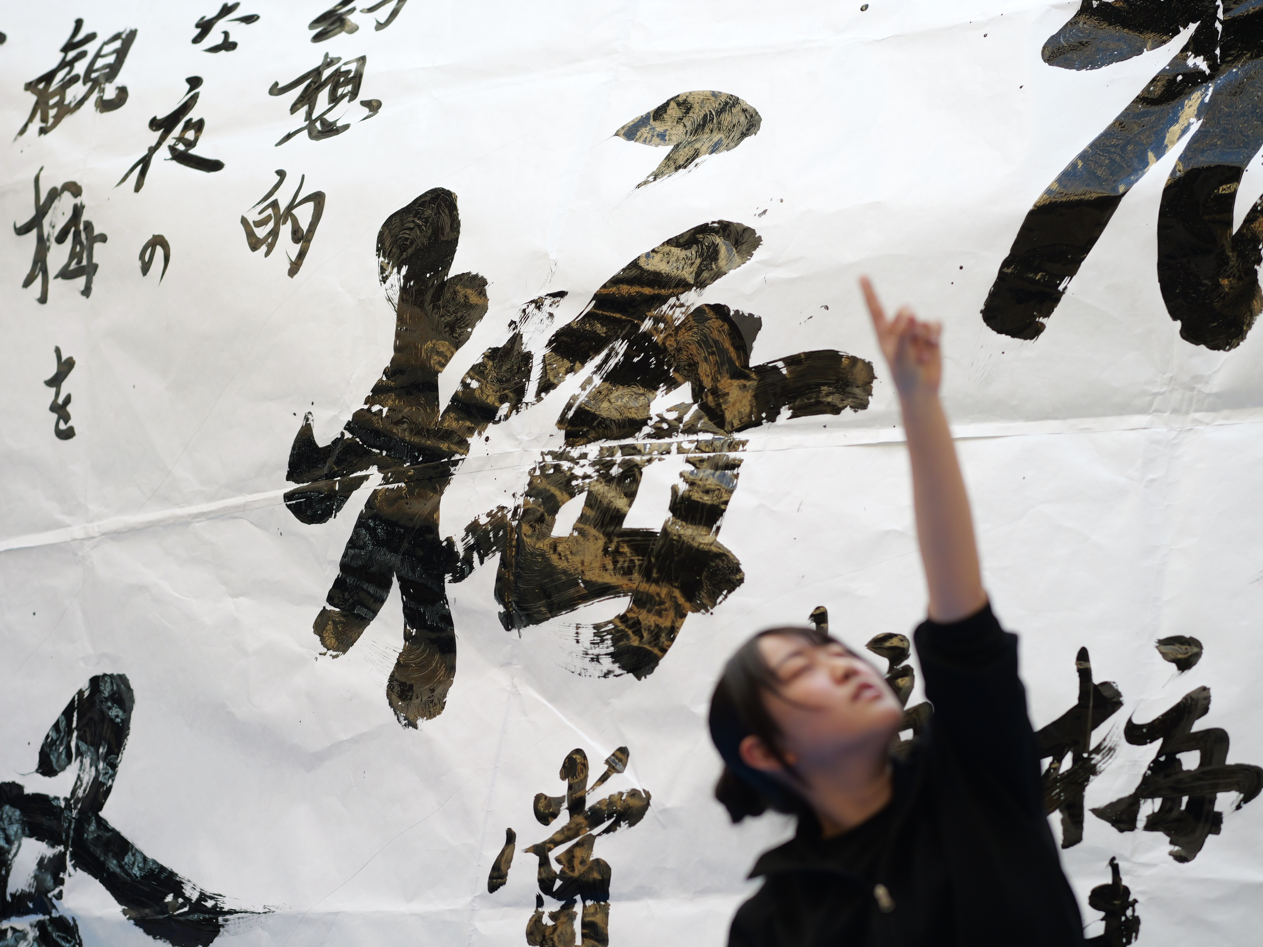 大きな紙面に「梅」が書かれている。その前で生徒がダンスをしている。