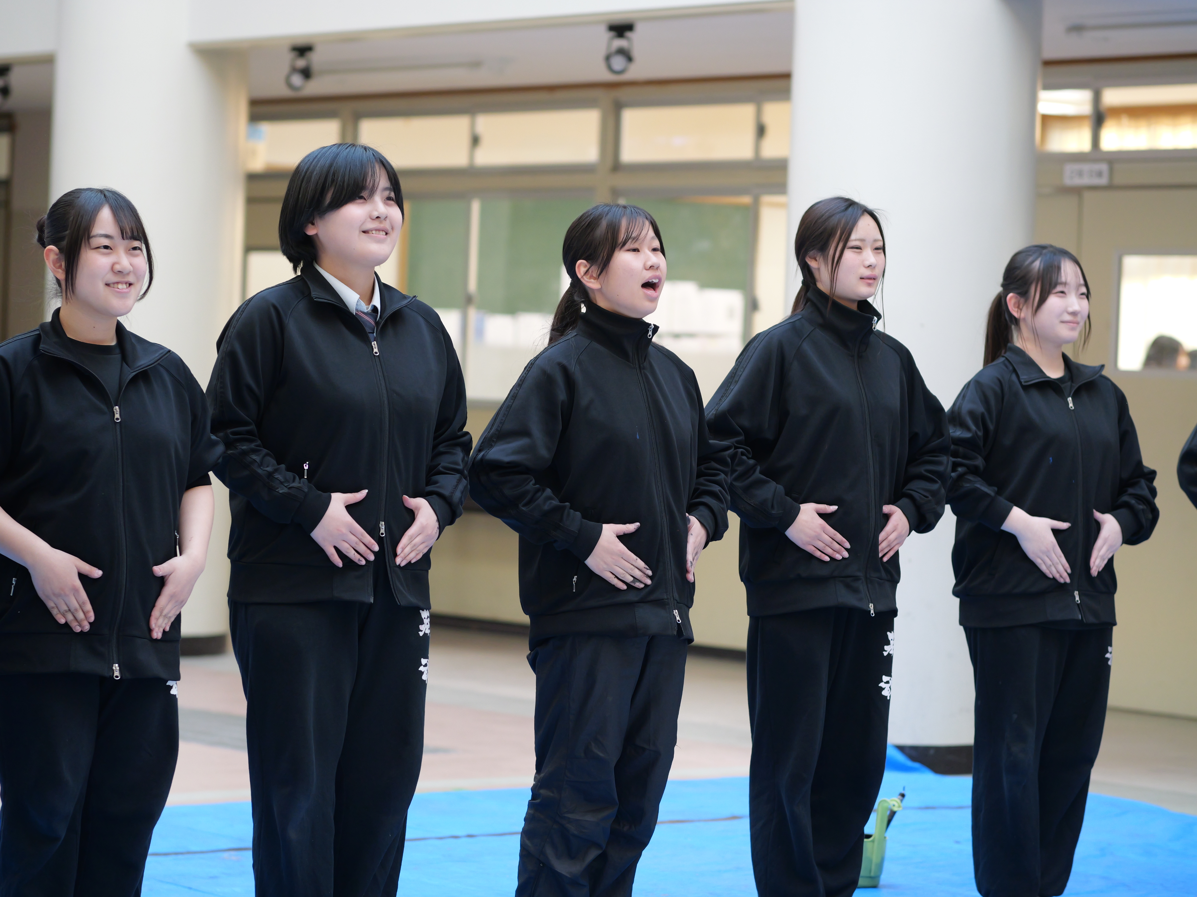 5人が並び、中央の部長がパフォーマンス前の挨拶をしている。