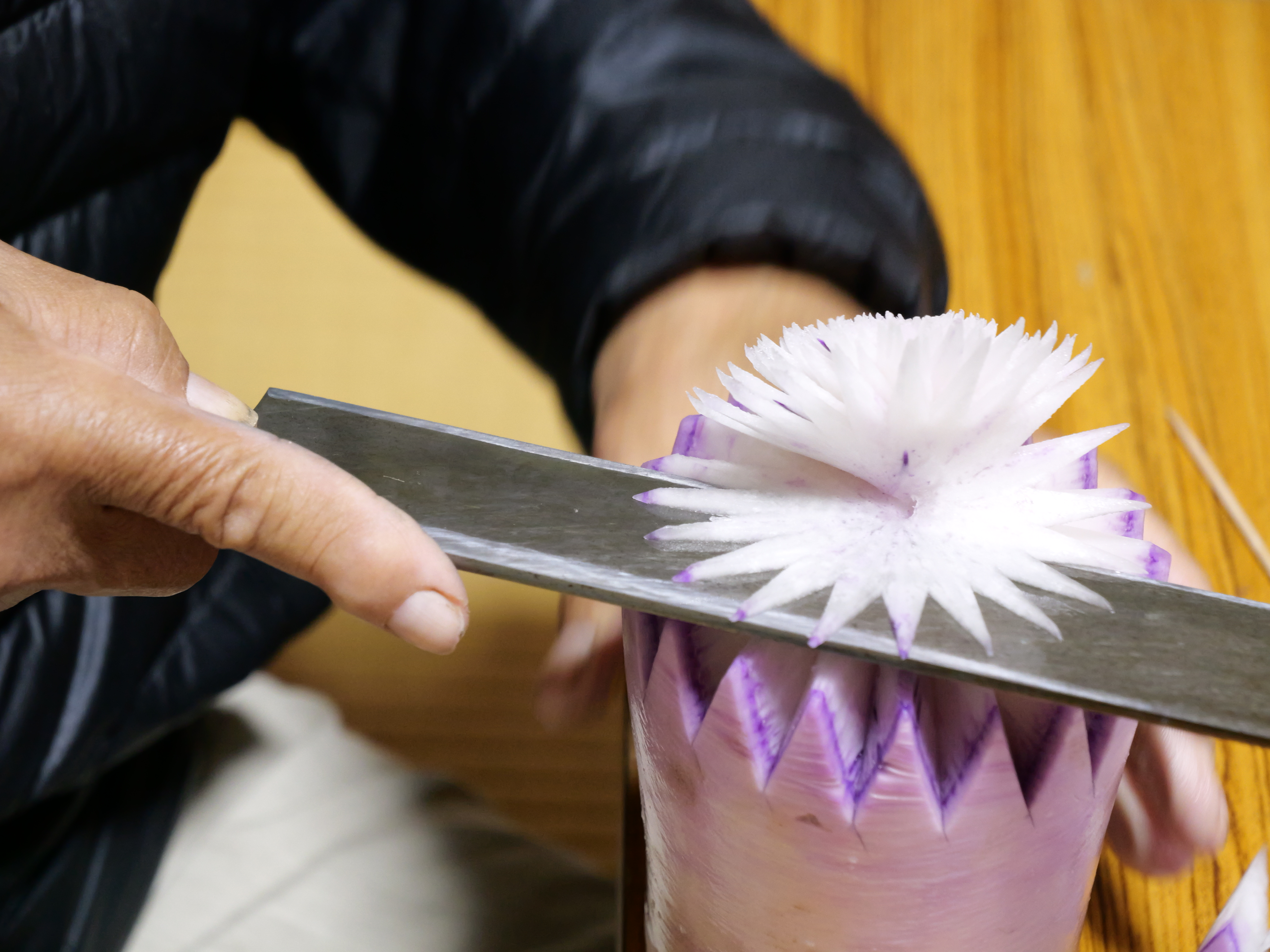 大根を回しながら切ってキクの花を作っている