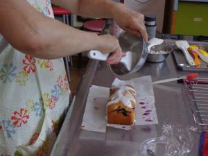 ケーキに仕上げのアイシングをしている写真です。