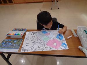 集中して凝ったデザインの絵を塗っている様子