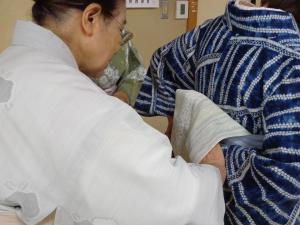 講師が帯のしめ方を教えている写真です。