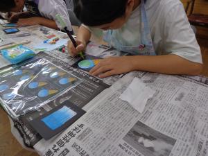 小学生がブラックボードに絵を描いている写真です