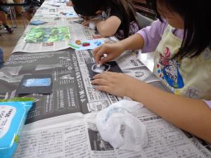 小学生がブラックボードにオイルパステルを使って色を塗っている写真です
