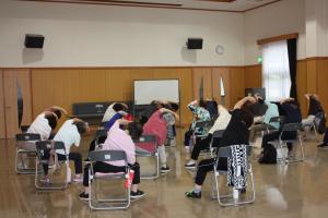 椅子に座ったまま右側に身体を曲げるストレッチの様子